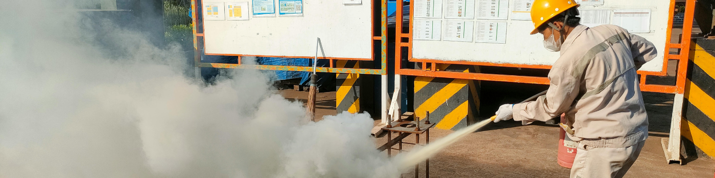 Worker conducts fire safety training outdoors with extinguishers.