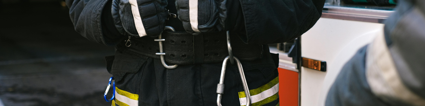 Firefighter in uniform with rescue equipment near emergency vehicle, highlighting safety and readiness.
