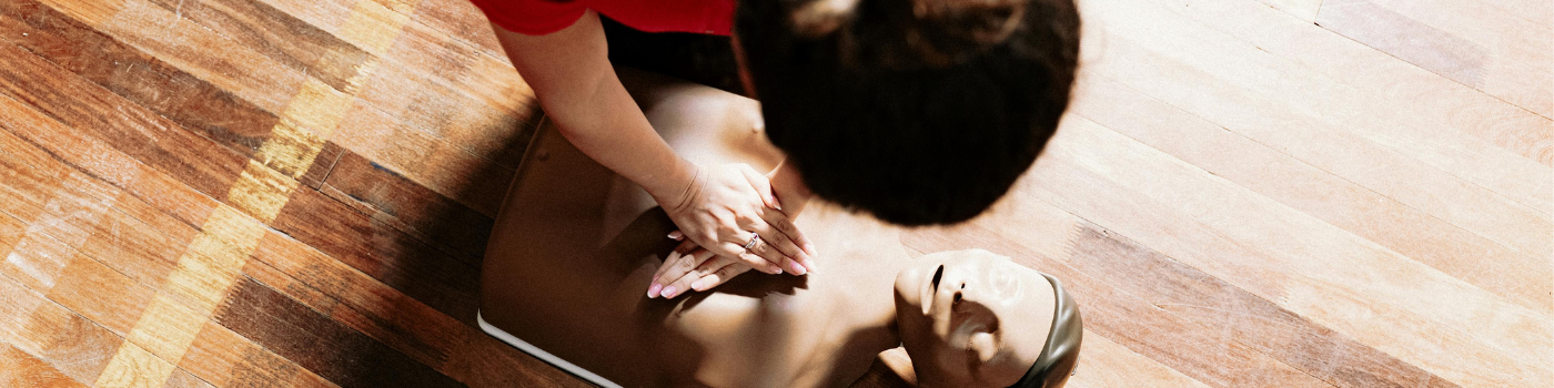 A person practices CPR on a training mannequin indoors