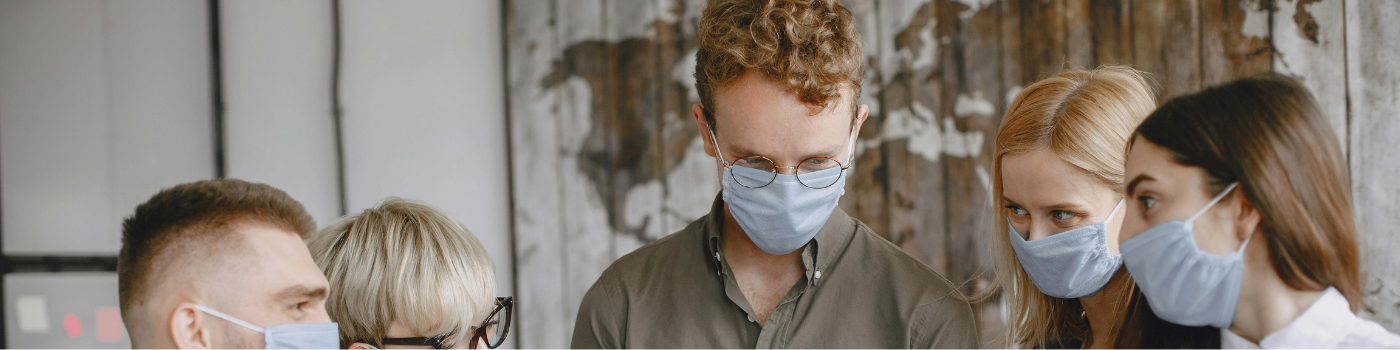 une réunion de travail en intérieur où plusieurs personnes portent des masques sanitaires, illustrant des protocoles de sécurité en entreprise